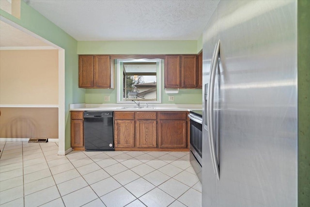 kitchen featuring sink, light tile patterned flooring, a textured ceiling, and appliances with stainless steel finishes