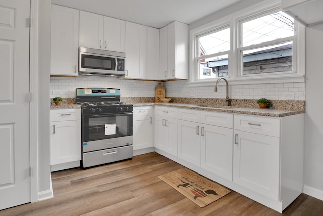 kitchen with white cabinets, light wood-type flooring, sink, and appliances with stainless steel finishes