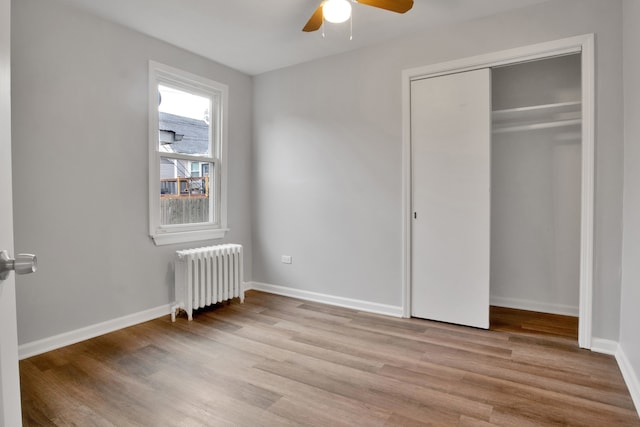 unfurnished bedroom featuring light wood-type flooring, a closet, radiator, and ceiling fan