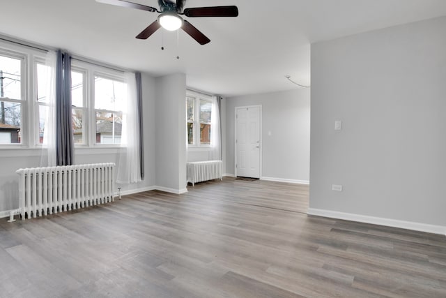 empty room featuring a healthy amount of sunlight, light hardwood / wood-style floors, and radiator