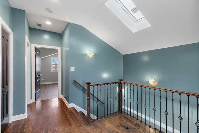 stairs with vaulted ceiling with skylight and wood-type flooring