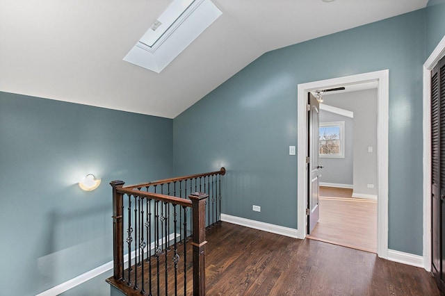 stairway featuring vaulted ceiling with skylight and hardwood / wood-style flooring