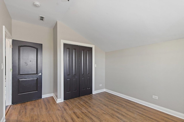 unfurnished bedroom featuring a closet, dark hardwood / wood-style flooring, and vaulted ceiling