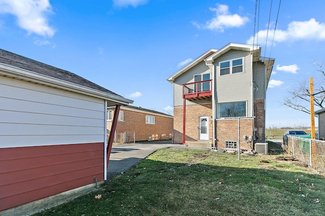 back of property with a balcony, cooling unit, and a lawn