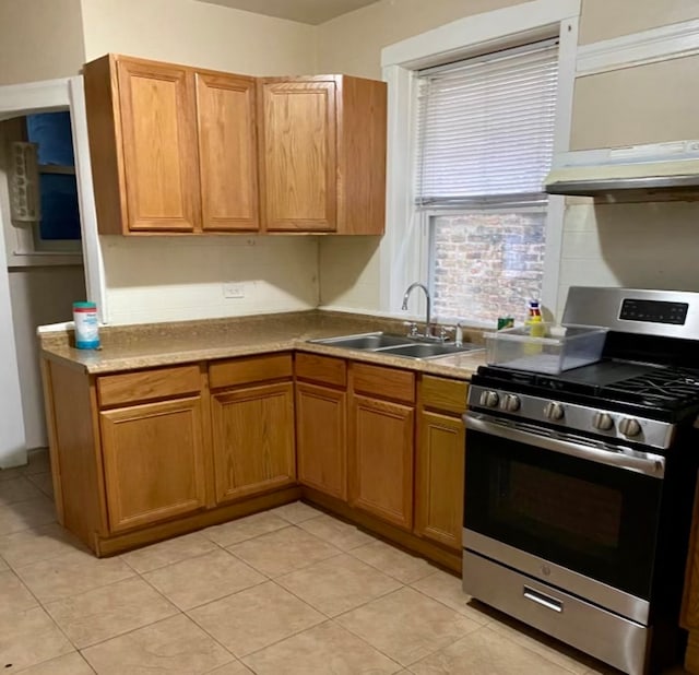 kitchen with light tile patterned flooring, sink, stainless steel range with gas cooktop, and range hood