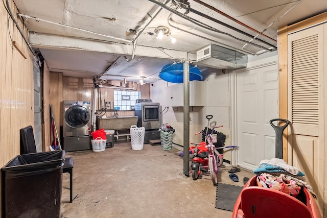 basement featuring washer / clothes dryer, wooden walls, and sink