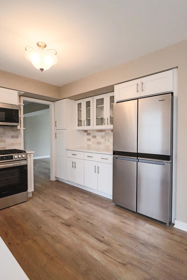 kitchen featuring stainless steel appliances, white cabinetry, tasteful backsplash, and light hardwood / wood-style floors