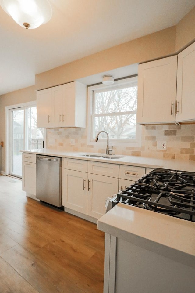 kitchen with white cabinetry, dishwasher, sink, and tasteful backsplash