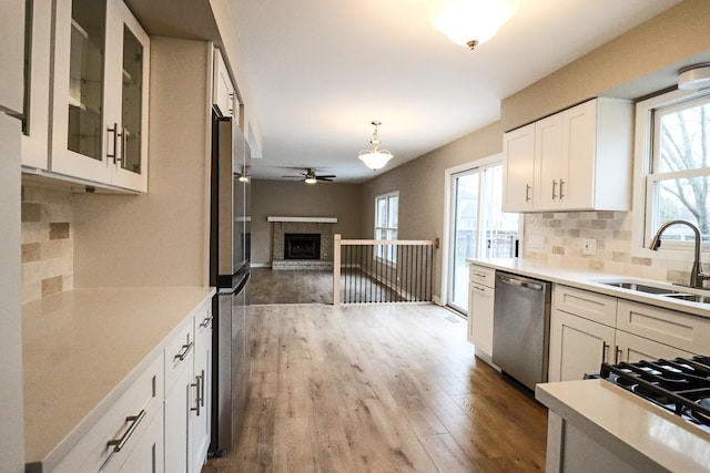 kitchen featuring appliances with stainless steel finishes, tasteful backsplash, sink, white cabinets, and hanging light fixtures