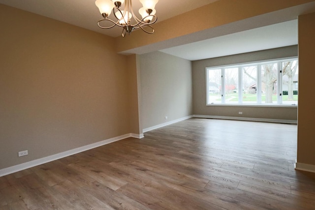 unfurnished room with wood-type flooring and a notable chandelier