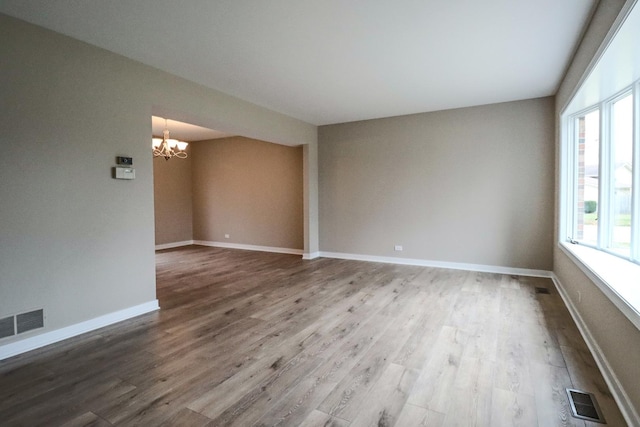 empty room with a notable chandelier and hardwood / wood-style flooring