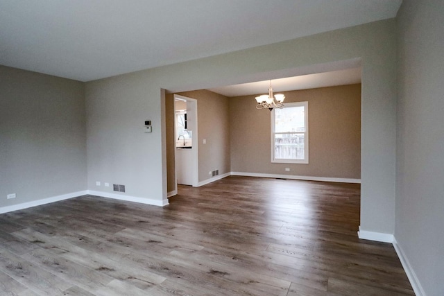 unfurnished room featuring an inviting chandelier and dark hardwood / wood-style floors