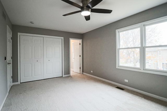 unfurnished bedroom featuring light colored carpet, ceiling fan, and a closet