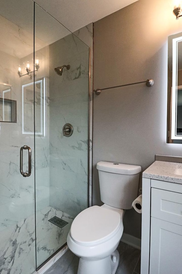 bathroom with vanity, a shower with shower door, and toilet