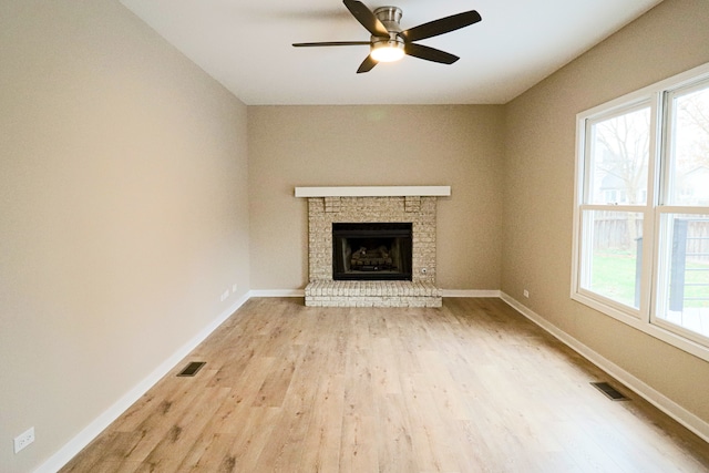 unfurnished living room featuring ceiling fan, a fireplace, and light wood-type flooring