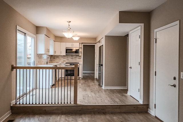 kitchen featuring decorative backsplash, light hardwood / wood-style floors, white cabinets, and appliances with stainless steel finishes