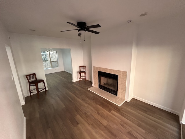 unfurnished living room with ceiling fan, dark wood-type flooring, and a tile fireplace