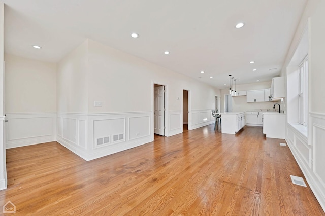 unfurnished living room with sink and light hardwood / wood-style floors