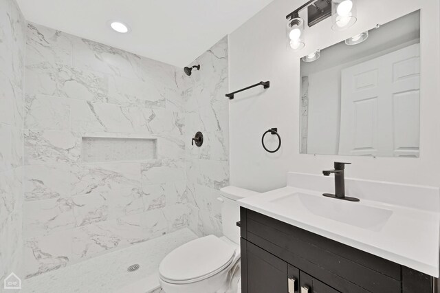 bathroom with vanity, toilet, and tiled shower