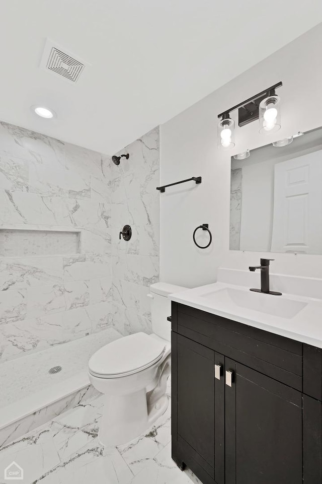 bathroom featuring tiled shower, vanity, and toilet