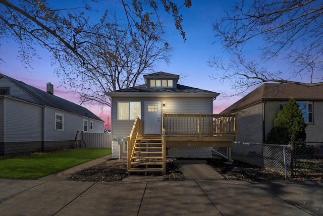 back house at dusk with a wooden deck