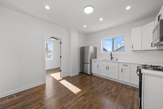 kitchen featuring ceiling fan, sink, stainless steel appliances, dark hardwood / wood-style flooring, and white cabinets