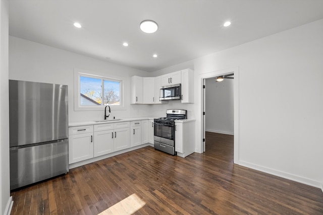 kitchen with appliances with stainless steel finishes, white cabinetry, dark wood-type flooring, and sink