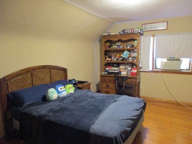 bedroom featuring hardwood / wood-style flooring, vaulted ceiling, and cooling unit