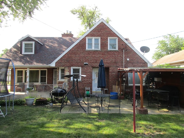 back of house featuring a lawn, a patio, and a trampoline