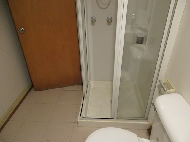 bathroom featuring tile patterned flooring, an enclosed shower, and toilet