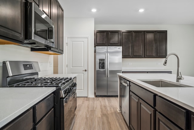 kitchen featuring dark brown cabinets, light hardwood / wood-style floors, sink, and appliances with stainless steel finishes