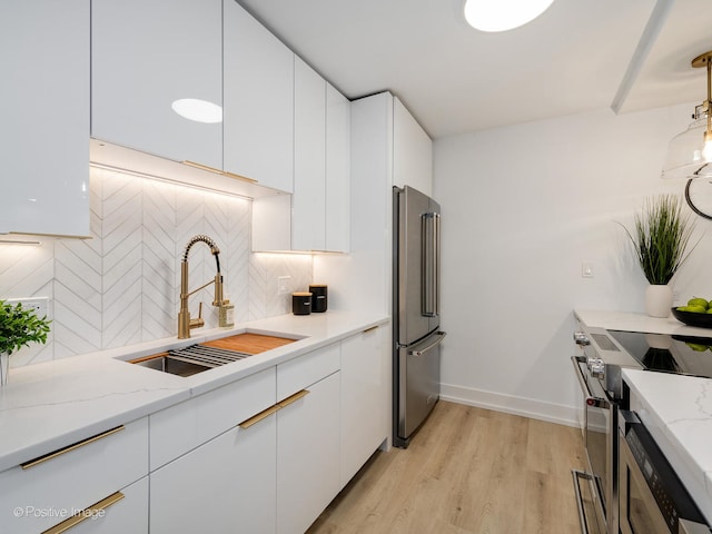 kitchen with high quality appliances, sink, white cabinets, and light hardwood / wood-style floors