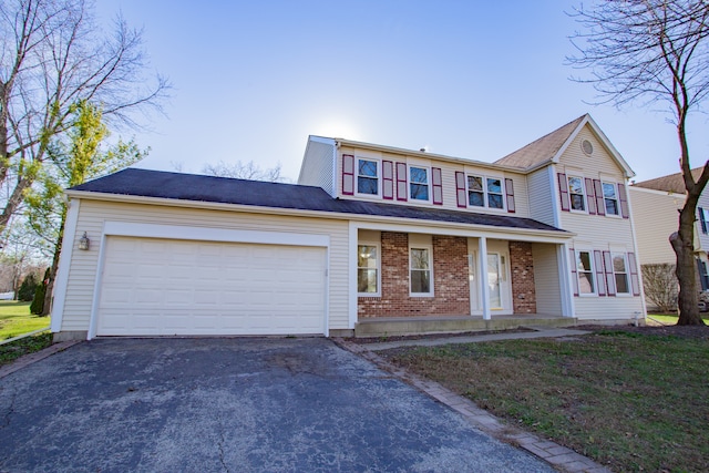 view of property with covered porch, a garage, and a front lawn