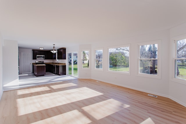 unfurnished living room featuring a healthy amount of sunlight and light wood-type flooring