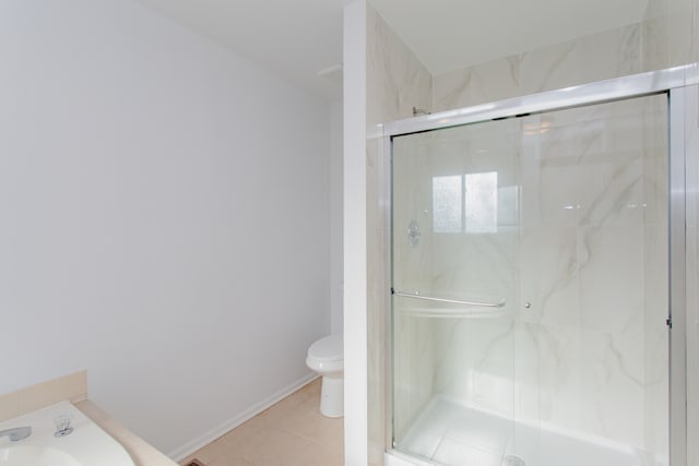 bathroom featuring tile patterned floors, toilet, and a shower with door