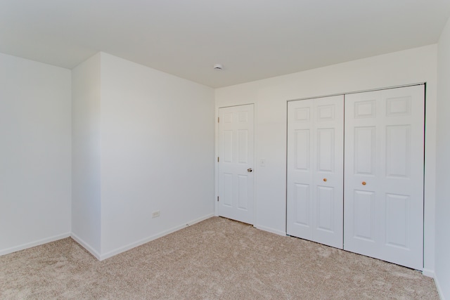 unfurnished bedroom featuring light carpet and a closet