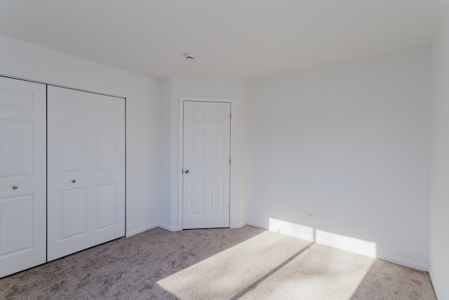 unfurnished bedroom with a closet and light colored carpet