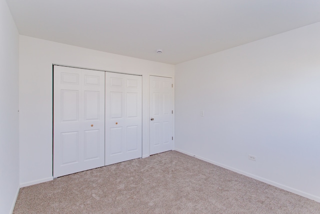 unfurnished bedroom featuring light carpet and a closet