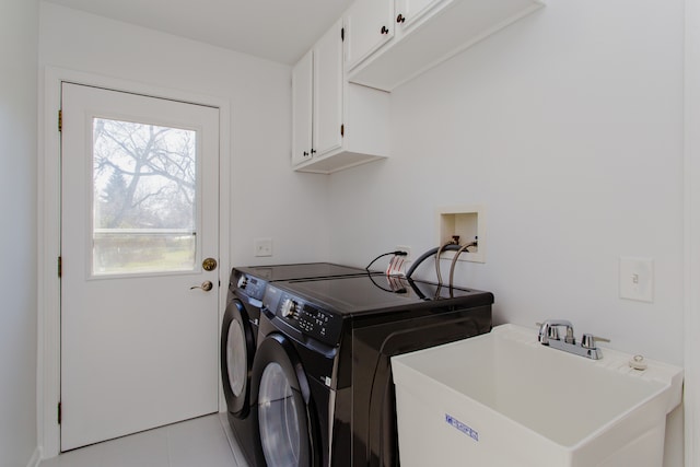 laundry room featuring cabinets, light tile patterned flooring, washing machine and clothes dryer, and sink