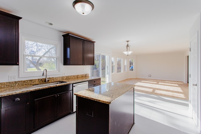 kitchen featuring sink, light stone counters, white dishwasher, decorative light fixtures, and a kitchen island