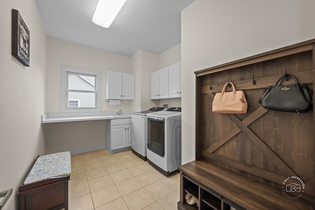 laundry room with cabinets, light tile patterned floors, separate washer and dryer, and sink