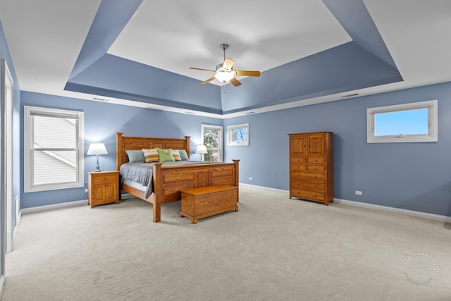 carpeted bedroom with ceiling fan and a tray ceiling