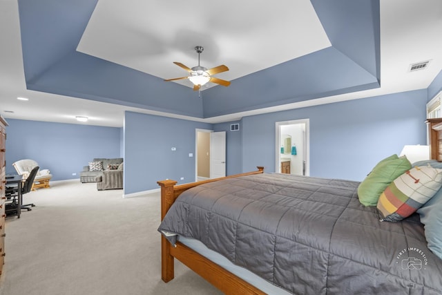 bedroom with light colored carpet, a raised ceiling, and ceiling fan