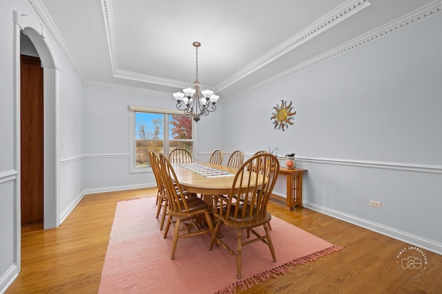 dining space featuring crown molding, light hardwood / wood-style flooring, and a chandelier