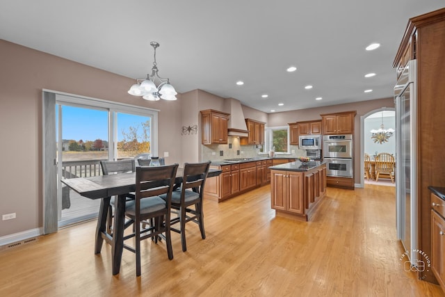 dining area with a notable chandelier, light hardwood / wood-style floors, and a healthy amount of sunlight