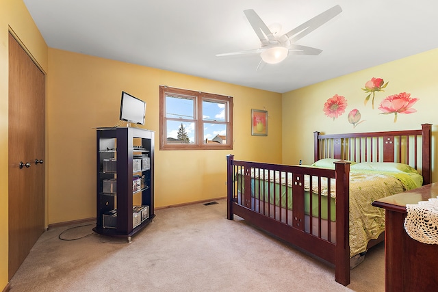 bedroom with ceiling fan, light colored carpet, and a closet