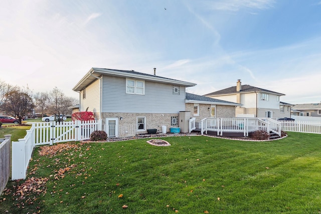 back of property featuring a lawn and a deck