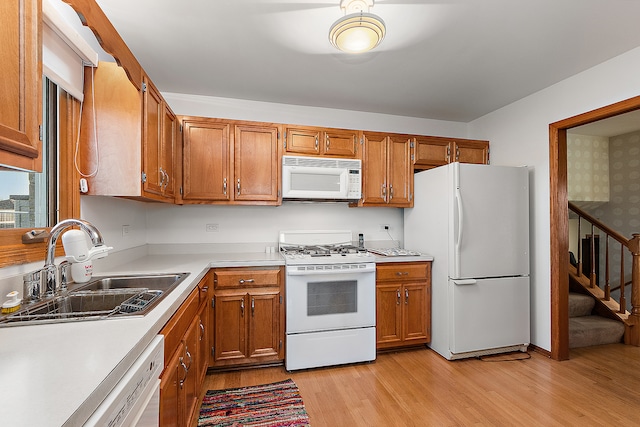 kitchen featuring sink, light hardwood / wood-style floors, and white appliances