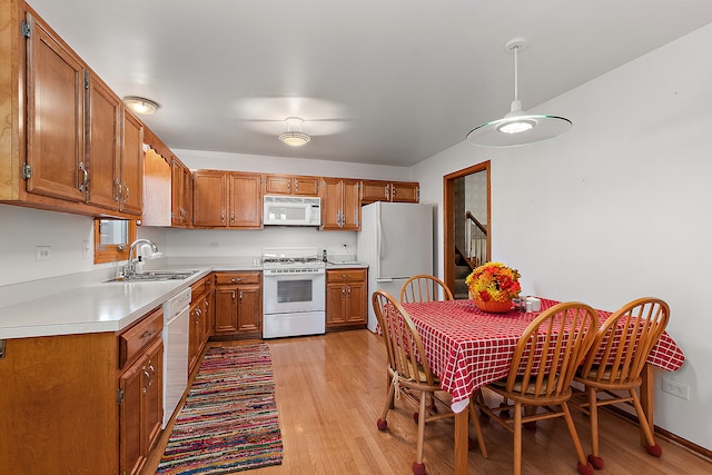 kitchen featuring sink, white appliances, and light wood-type flooring