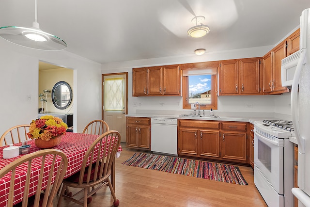 kitchen with light hardwood / wood-style flooring, pendant lighting, white appliances, and sink